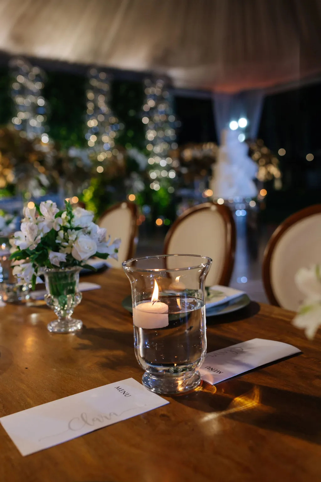 Mesa posta com vela e flores brancas na festa